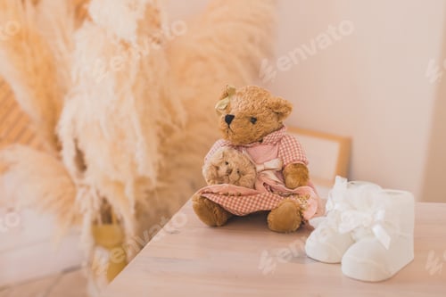 Preview: Cute small teddy bear is sitting near small white shoes for small newborn baby
