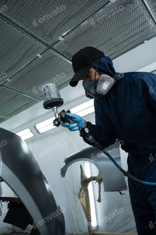 Preview: Mechanic spraying dark coat on car wearing gloves