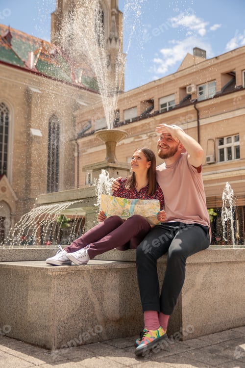 Preview: Young Two People, Sitting Near Fountain In An Old City Square. Admiring To Local European