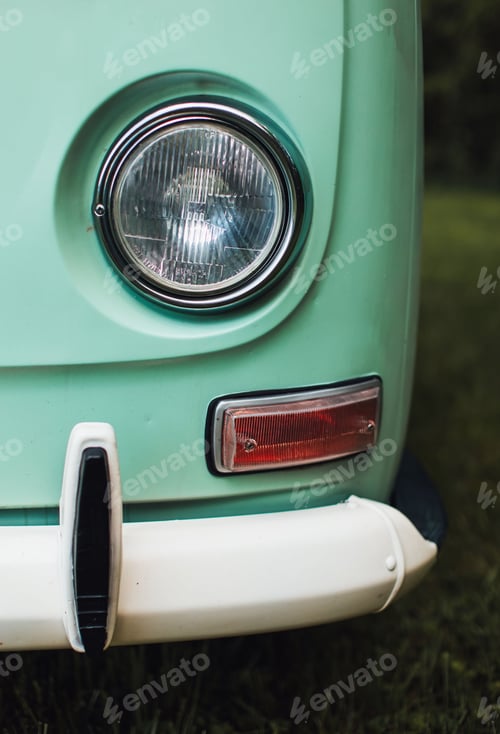 Preview: Vertical closeup shot of a headlight of a turquoise retro van