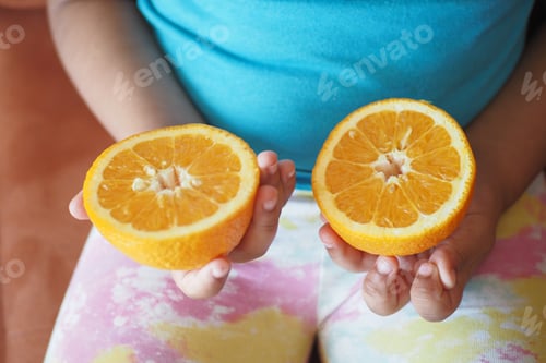 Preview: child holding slice of orange fruit