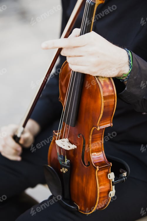 Preview: Classical musicians hold their musical instrument, a violin, while reading their score.