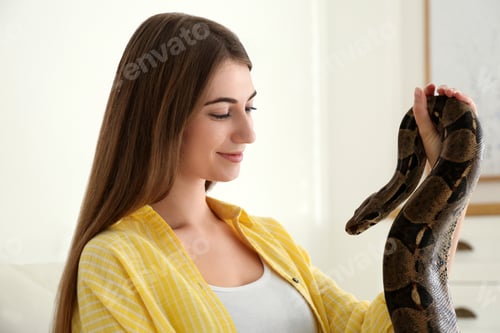 Preview: Young woman with boa constrictor at home. Exotic pet
