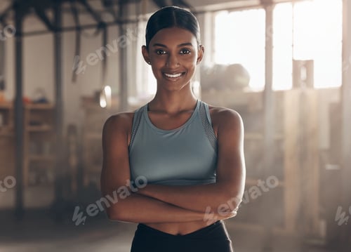 Preview: Portrait of a sporty young woman standing with her arms crossed in a gym