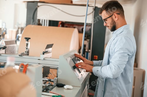 Preview: Operating printing cutting machine. Print house worker in white clothes is indoors