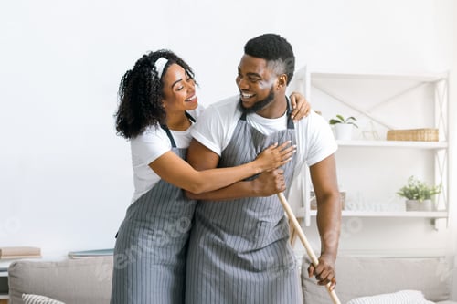 Preview: Happy black couple doing household chores together, mopping floor and hugging