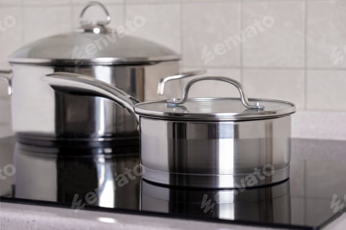 Preview: Ladle and large saucepan stand on modern stove with glass-ceramic hob