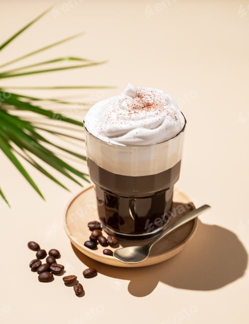 Preview: Iced coffee in a glass with foam on a yellow background with coffee beans, palm leaf and shadows.
