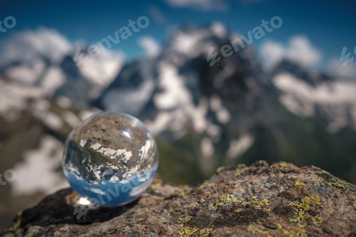 Preview: Transparent glass sphere and snow-capped peaks in the background. Concept and idea of travel