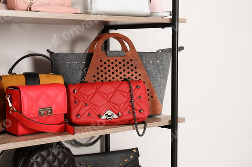 Preview: Shelving unit with stylish purses near white wall. Element of dressing room interior