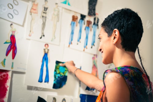 Preview: Female Fashion Designer Contemplating Drawings In Studio
