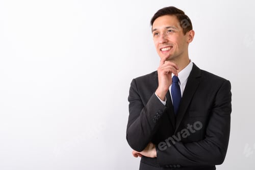 Preview: Studio shot of young happy businessman smiling and thinking whil