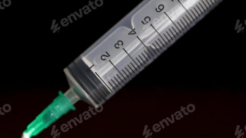 Preview: Medical syringe with liquid on black background. Water drop from syringe needle. Close up. research