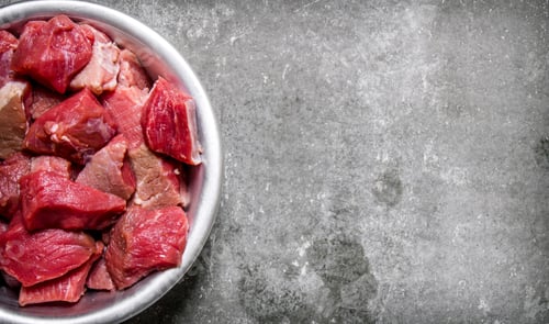 Preview: Chopped raw meat in a cup. On stone table.