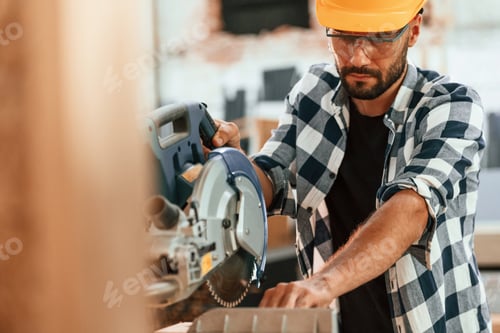 Preview: Using the saw to cut the wood. Industrial worker in warehouse