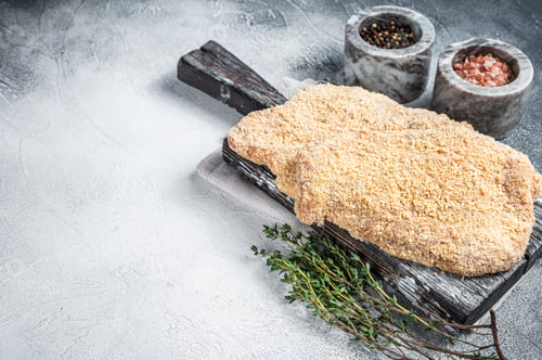 Preview: Wiener Raw schnitzel in breadcrumbs on wooden board. White background. Top view. Copy space