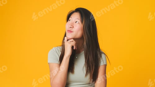 Preview: Girl in gray top looking at camera, smiling and flirting isolated on yellow background in studio