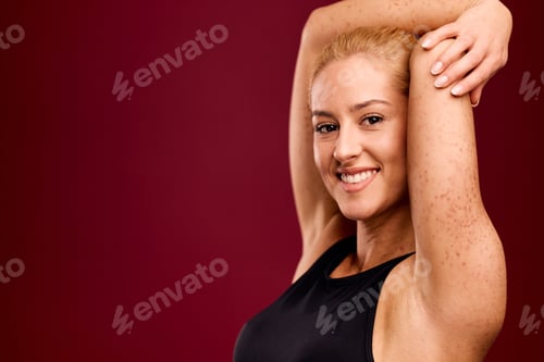 Preview: Portrait of a happy female with spotted skin and her hands behind a head.