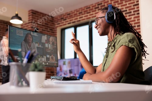 Preview: African american startup employee in video conference with team making ok hand sign