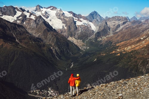 Preview: Young couple doing Nordic walking in the mountains, rear view. An active couple is engaged in Hiking