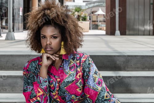 Preview: Confident ethnic woman with afro hairstyle sitting on stairs