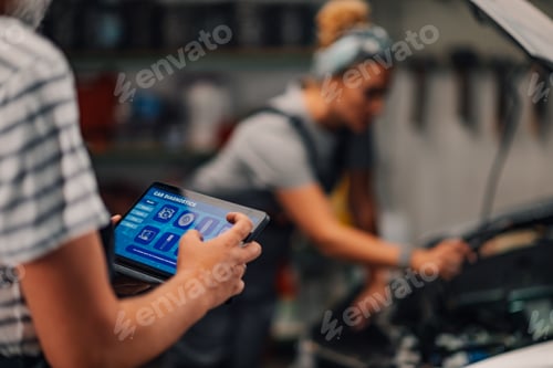 Preview: Close up of auto mechanic's hands with tablet and doing car diagnostics