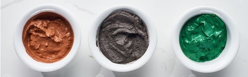 Preview: panoramic shot of cups with brown, gray and green clay mask on marble surface