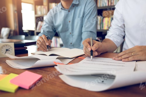 Preview: Asian young university students studying together sitting at desk in library.