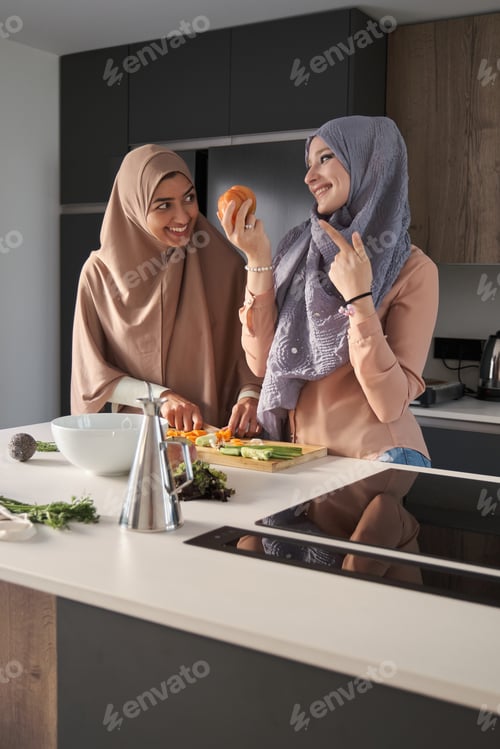 Preview: Two muslim women preparing a salad at modern kitchen.