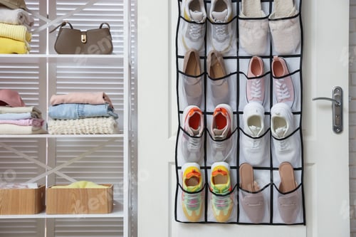 Preview: Organizer with different footwear on door, accessories and clothes indoors. Shoe storage