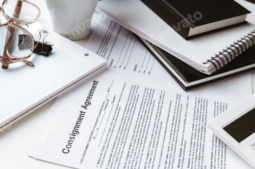 Preview: Office workspace with consignment agreement and supplies scattered on table