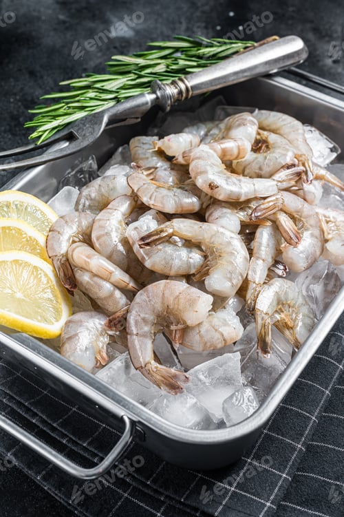 Preview: Raw pacific white shrimp prawn peeled with tail on ice. Black background. Top view