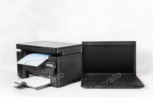 Preview: Printer and laptop set up for work with printed document on a white background