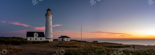 Preview: the lighthouse is lit up at night on the beach at sunset