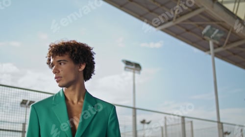 Preview: Curly student looking camera at stadium fashion portrait. Serious model posing
