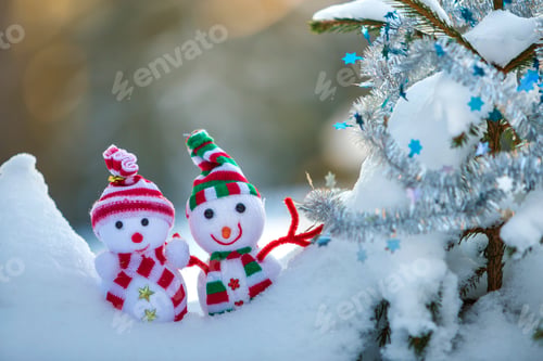 Preview: Two small funny toys baby snowman in knitted hats and scarves in deep snow outdoors