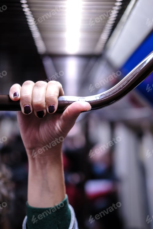Preview: Vertical picture of a hand holding metal bar in a public transport