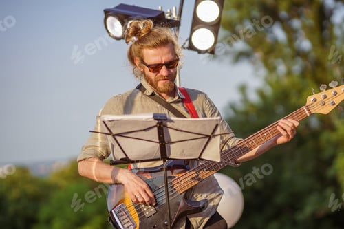 Preview: Bearded Musician Plays Bass Guitar Outdoors in Sunlight