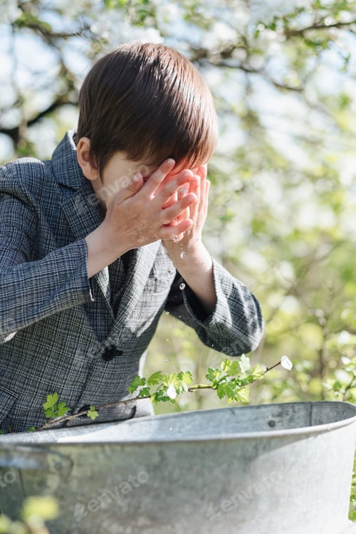 Preview: boy washes himself with clean water from an iron basin with delicate flowers