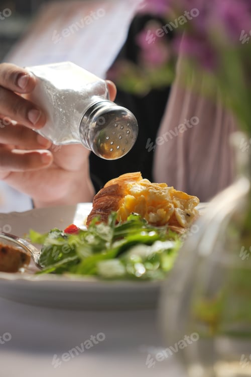 Preview: Adding seasoning to a fresh salad on a dining table