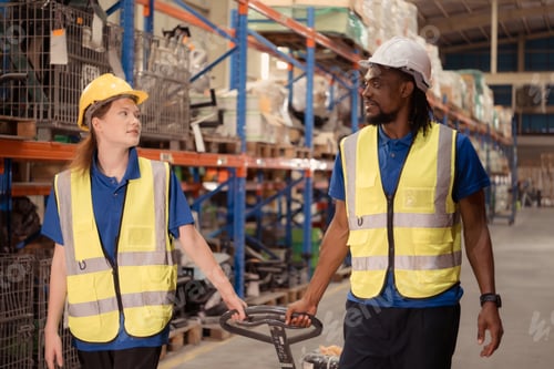 Preview: Top view of two warehouse workers pushing a pallet truck in a shipping and distribution warehouse.