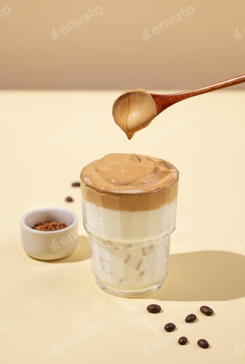 Preview: Dalgona coffee. Whipped instant coffee with ice and milk on a yellow background with shadow.