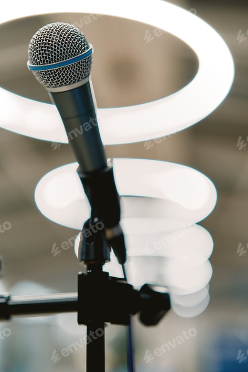 Preview: Microphone stands on the stage against the backdrop of glowing lamps
