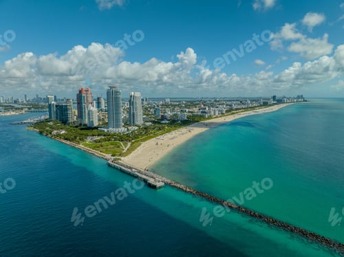 Preview: Aerial view of Miami Beach with high-rise buildings, a sandy beach, and ocean under a blue sky