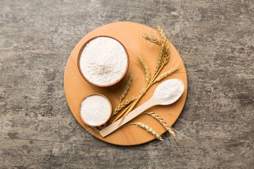 Preview: Flat lay of Wheat flour in wooden bowl with wheat spikelets on colored background