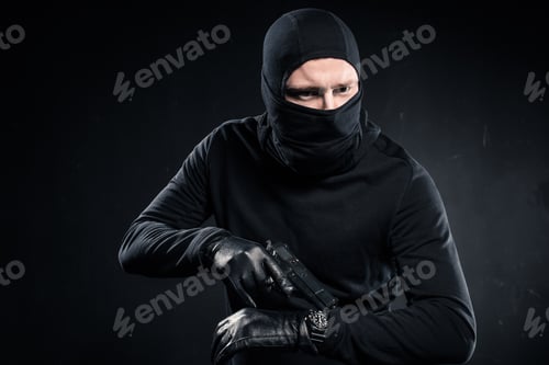 Preview: Male criminal in gloves with gun checking his watch