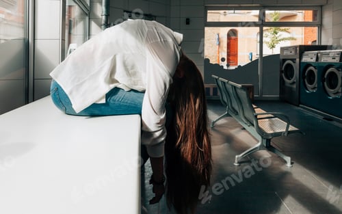 Vista previa: young woman waiting in an empty laundry