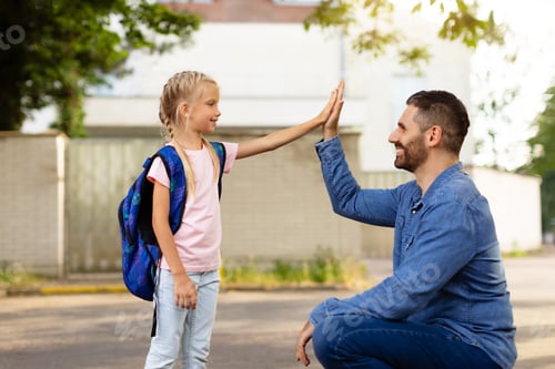 Preview: Father-daughter bonding. Parent and pupil of primary school giving high five and smiling at each