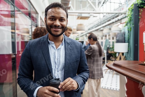 Preview: Portrait of indian businessman standing in modern office on colleagues background