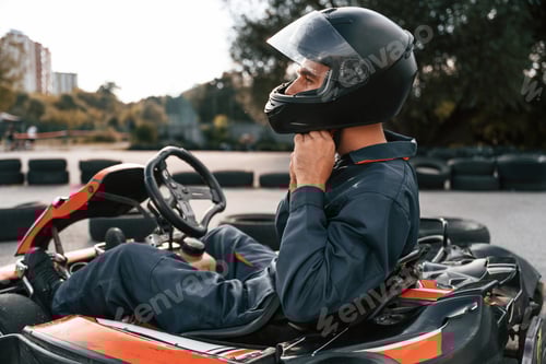 Preview: Side view, wearing the safety helmet. Man is outdoors, kart racing conception